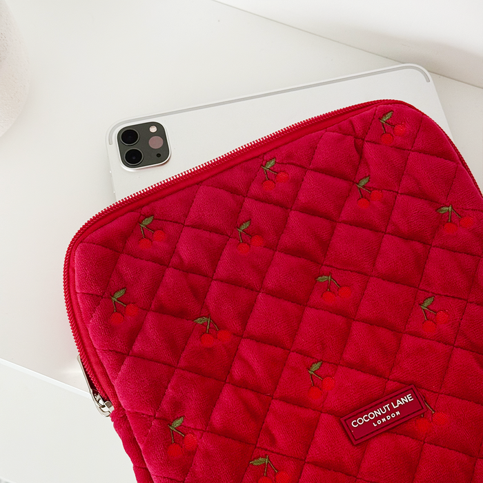 Quilted cherry red velvet iPad sleeve with small cherry pattern, holding a tablet.