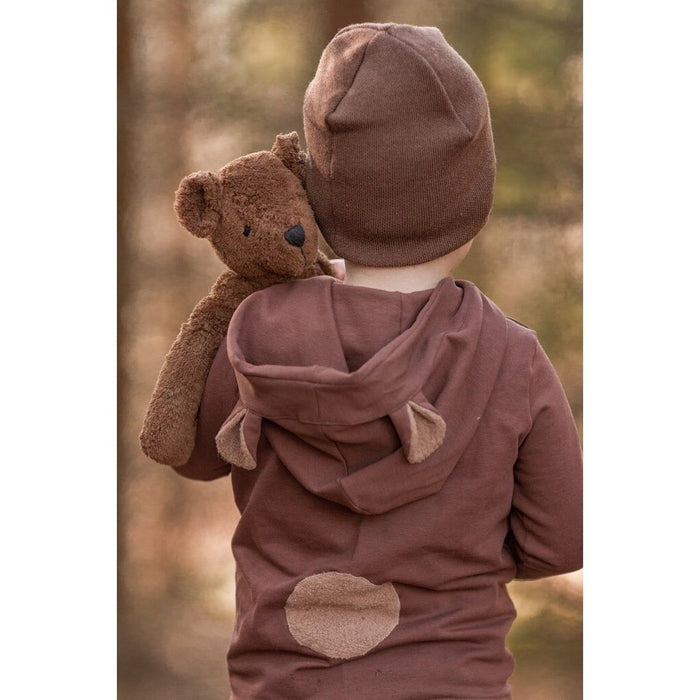 Child wearing a brown outfit with a hood and bear ears, holding a Brown Senger teddy bear.