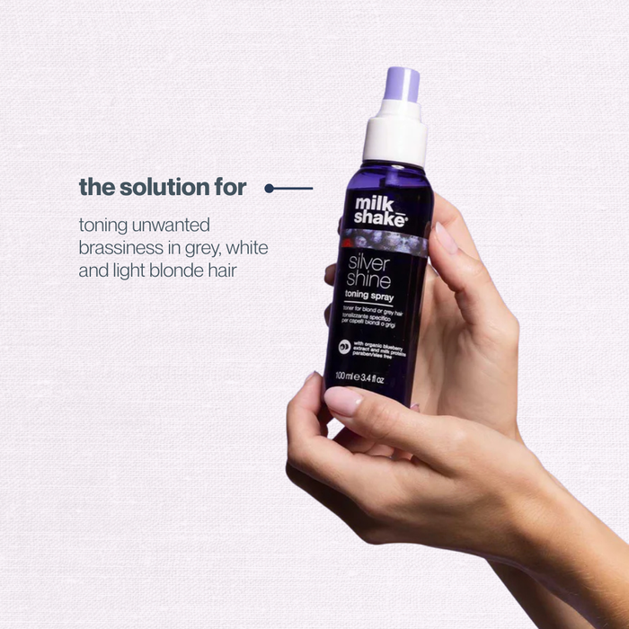 Hand holding a bottle of 'milk_shake' Silver Shine product against a light purple background