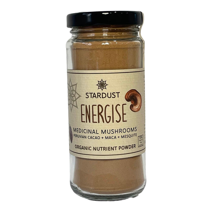 A glass jar of Stardust Energise Medicinal Mushrooms organic nutrient powder, featuring a beige label and a black lid, set against a plain white background.