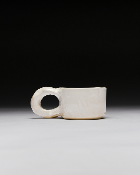 White ceramic cup and object with a circular handle on a black, gray and white background