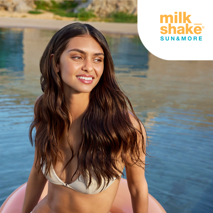 Woman in a bikini sitting on a pink float by a body of water with 'milk_shake' branding.