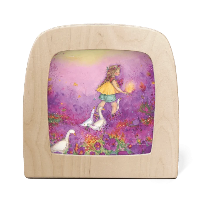 Wooden frame with silhouette of a girl in a purple flower field followed by white geese