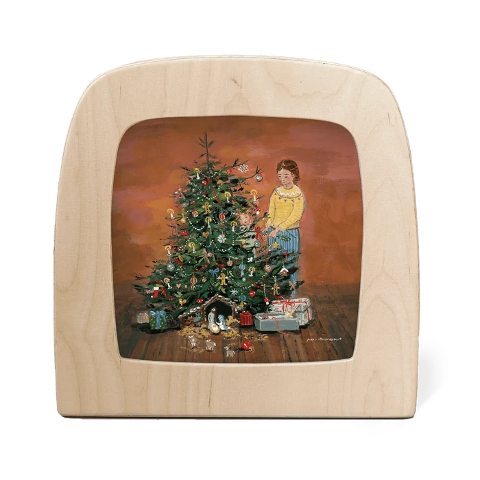 Silhouette of a mother and child decorating a Christmas tree, with presents and a nativity scene at the base