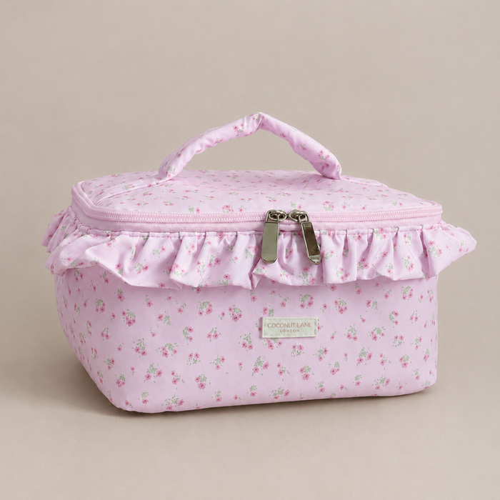 Pink floral patterned Vanity Bag with ruffled trim, handle and zip closure.