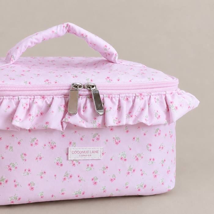 Pink floral patterned Vanity Bag with ruffled trim, handle and zip closure.