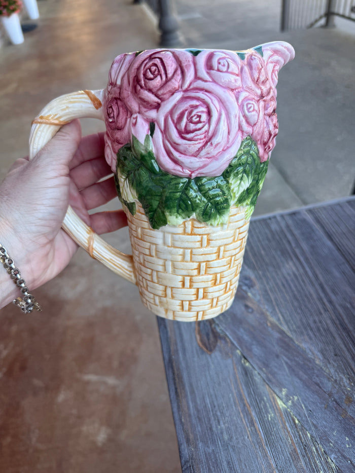 Cat-shaped mug with floral design held by a hand against a wooden surface.