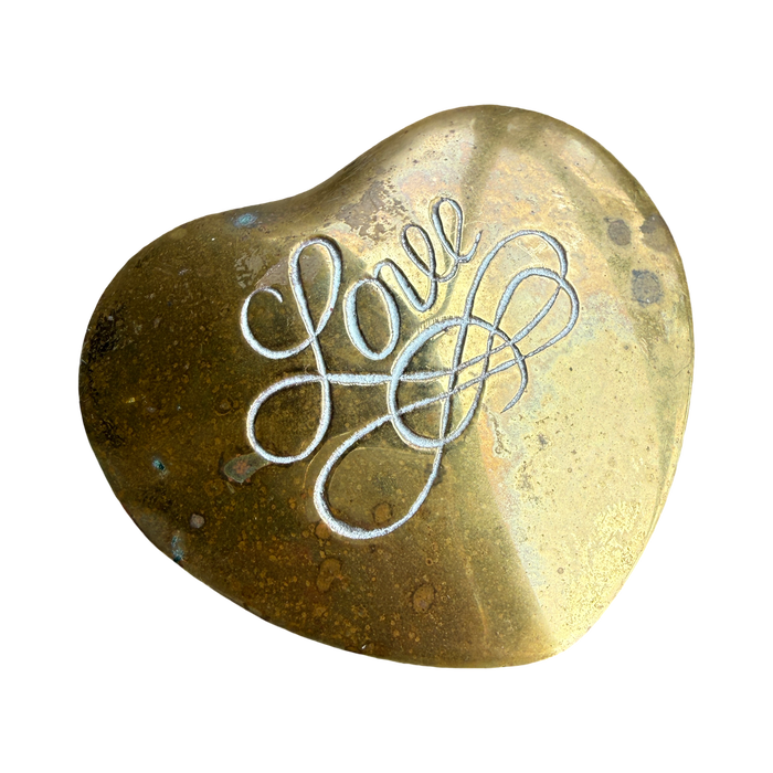 Heart-shaped brass object with 'Love' engraved on a white background