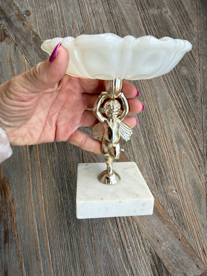 Decorative wall sconce with marble-like finish held by a hand on a wooden surface