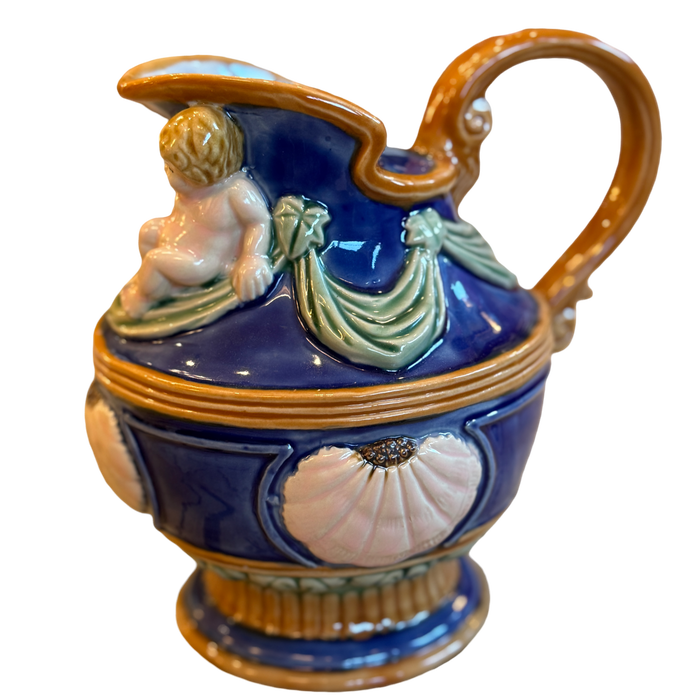 Decorative ceramic pitcher with a handle and figurine on a white background