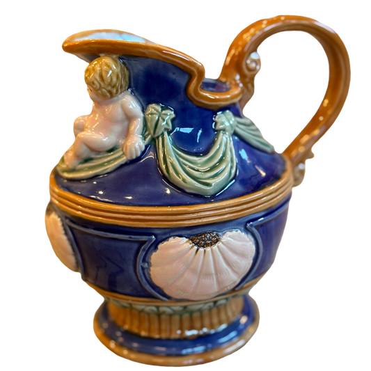 Decorative ceramic pitcher with a handle and figurine on a white background