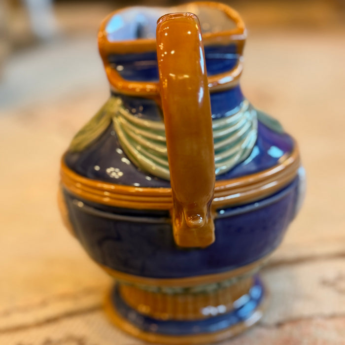 Ceramic pitcher with blue and gold design on a textured surface