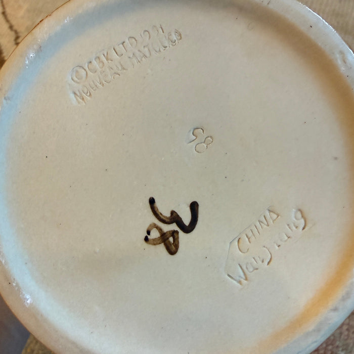 Ceramic plate with visible branding and number on a textured surface