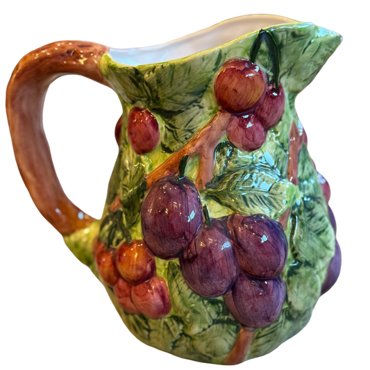 Ceramic pitcher with grape design on a white background