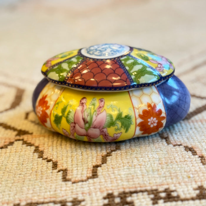 Decorative tin box with colorful design on a textured surface