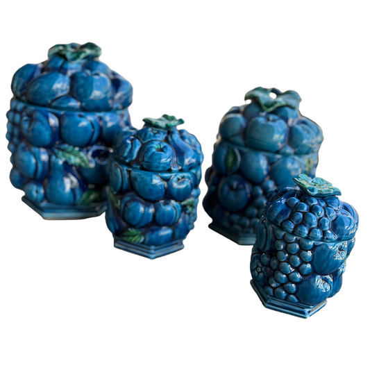 Set of four blue ceramic jars with grape design on a white background