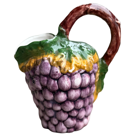 Ceramic teapot shaped like an acorn with purple grapes on a white background