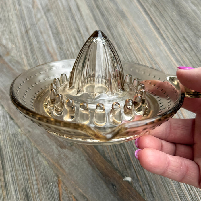 Hand holding a clear glass jellyfish ornament on a wooden surface