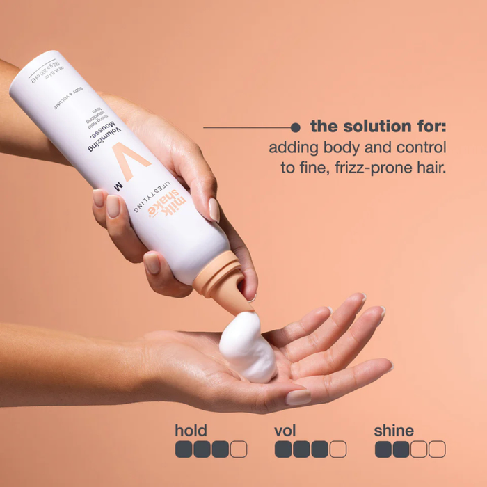 Hand holding a bottle of milk_shake  volumizing mousse with text on a beige background