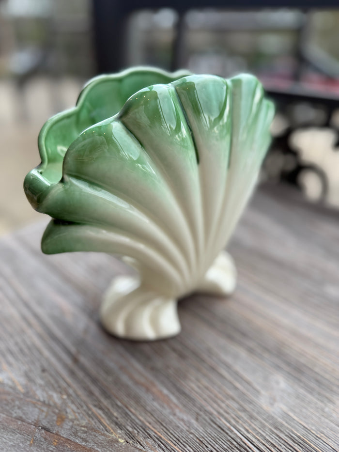 Ceramic shell-shaped vase on a wooden surface